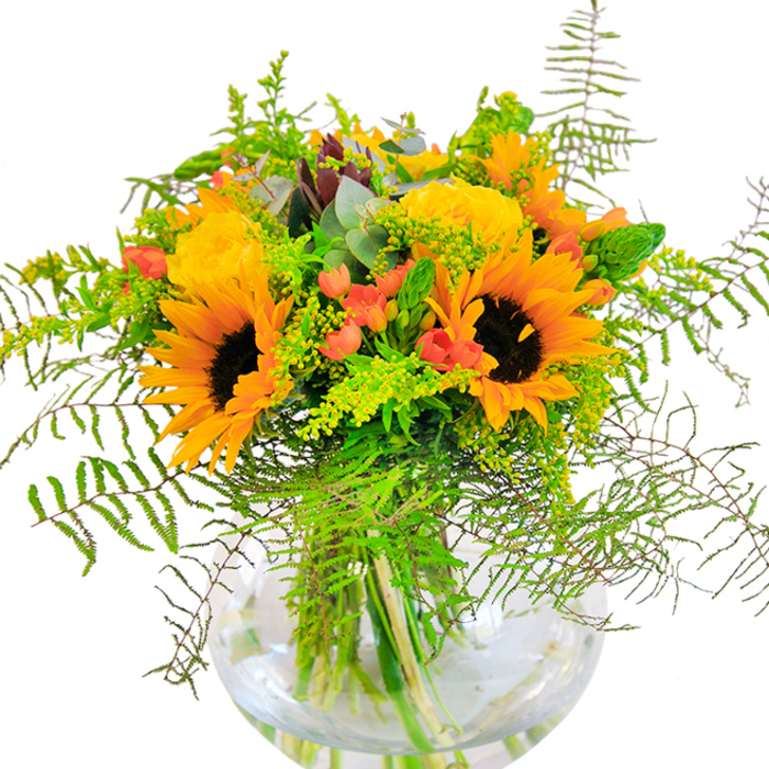 The first impression of this abundant bouquet, lovingly created for Temple, is one of pure radiance-a dazzling composition where sunflowers and golden garden roses catch the eye, their petals unfurling with the vibrant energy of a city afternoon. The bouquet sits in a round, crystal-clear glass vase, proudly revealing the vivid green stems that anchor this display much like the historic pillars of Temple Church. Deep, velvety sunflowers take centre stage, their brown and gold hearts glowing with an air of confidence and joy, closely surrounded by buttery yellow roses with delicately layered petals that evoke classic beauty. Wisps of feathery ferns and soft, light green sprigs cascade gracefully, their movement echoing the gentle breeze that crosses Temple's hidden courtyards. Playful red hypericum berries are nestled among the rich foliage, their glossy skin offering jewel-like flashes that set off the softer bloom tones. Hints of silvery eucalyptus and slender green flower spikes lend freshness and modern flair, balancing the composition perfectly. As you take in the bouquet, the subtle interplay of matte and glossy textures unfolds, and if you lean close, the fragrance is a gentle blend-sweet rose, crisp greenery, and the faintest whisper of autumn air. This handcrafted arrangement is ideal for marking significant occasions-a birthday, a promotion, or any day that calls for happiness at the heart. Available for same-day flower delivery across Temple and the surrounding legal quarter, it embodies both nature's bounty and the care of expert local florists.